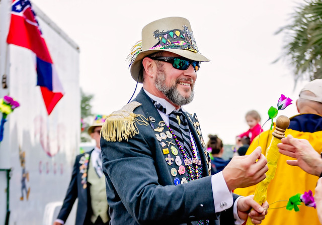 Ole Biloxi Marching Club giving flowers at Krewe de la Dauphin Mardi Gras parade in Dauphin Island, Alabama